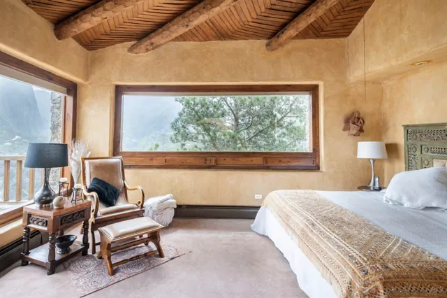 Recámara con vigas de madera y ventanal al valle en Casa Patagalana